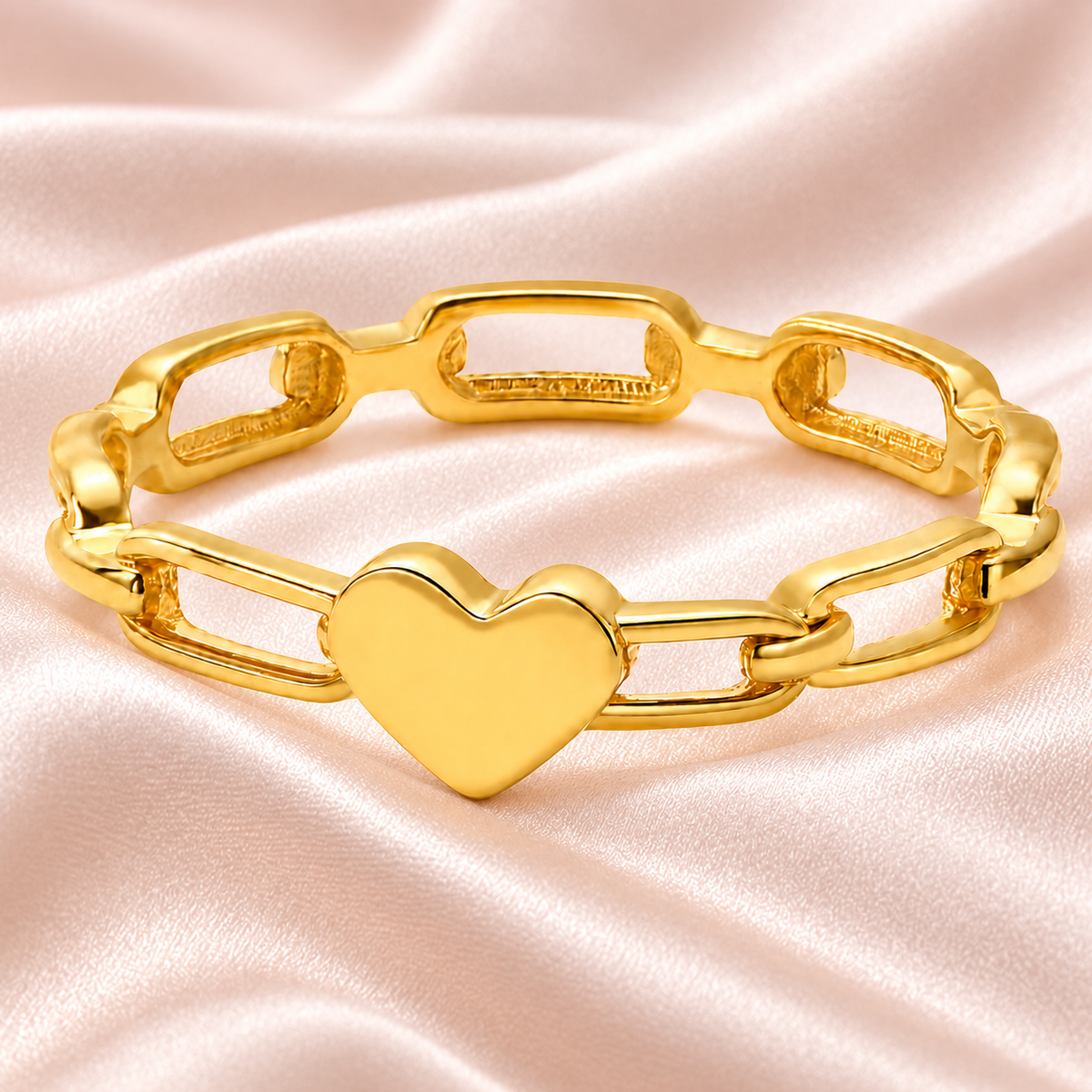 Gold-tone heart link ring, still-life view on fabric.
